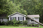 Fallen tree on top of grey bungalow house