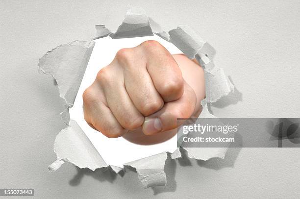 fist punching through a ripped hole in a paper - emerge stock pictures, royalty-free photos & images