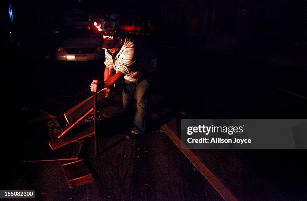 Man breaks wood for a bonfire October 31, 2012 in New York City. At least 15 people were reported killed in the United States by Sandy as millions of...