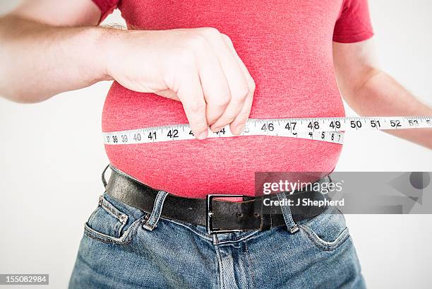 a middle-aged man measuring his large belly - man in tight pants stock pictures, royalty-free photos & images