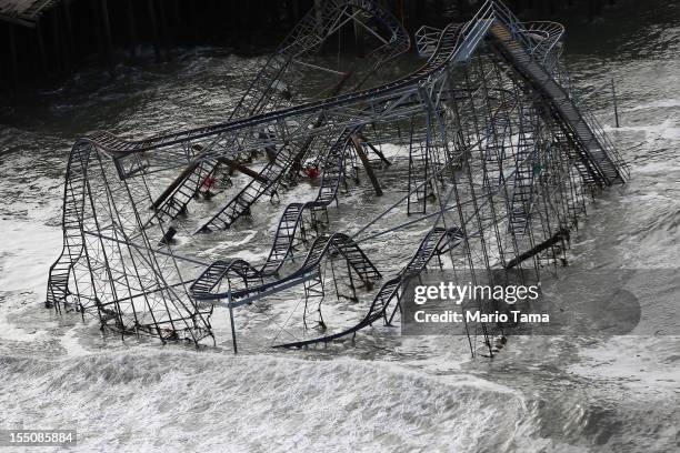 Surf rolls past a destroyed roller coaster wrecked by Superstorm Sandy on October 31, 2012 in Seaside Heights, New Jersey. At least 50 people were...