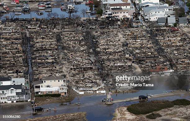 People gather around the remains of burned homes after Superstorm Sandy on October 31, 2012 in the Breezy Point neighborhood of the Queens borough of...