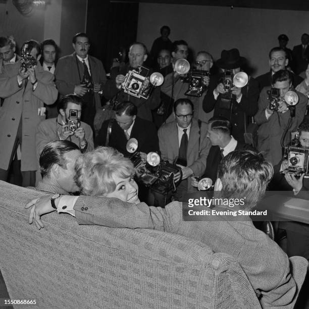 Members of the press take pictures of French actress Brigitte Bardot following her arrival at London Airport for the filming of 'Babette Goes To...