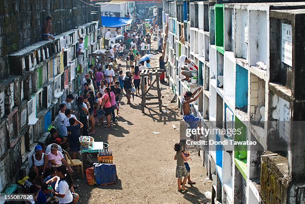 Families gather to pray, light candles and clean tombstones of the departed at the Navotas public cemetery on November 1, 2011 in Manila,...