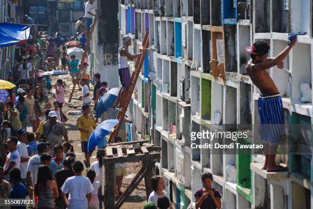 Families gather to pray, light candles and clean tombstones of the departed at the Navotas public cemetery on November 1, 2011 in Manila,...