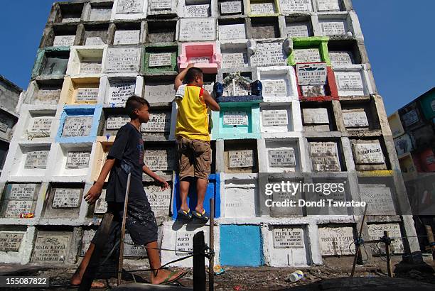 Families pray and light candles on tombstones of the departed at the Navotas public cemetery on November 1, 2011 in Manila, Philippines. The 'Day of...