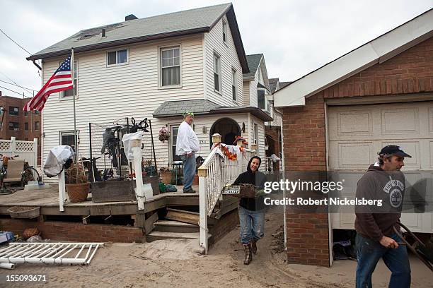 Jim Luongo and his neighbors clear debris from their homes in Rockaway Beach after Superstorm Sandy hit during the previous night on October 31, 2012...