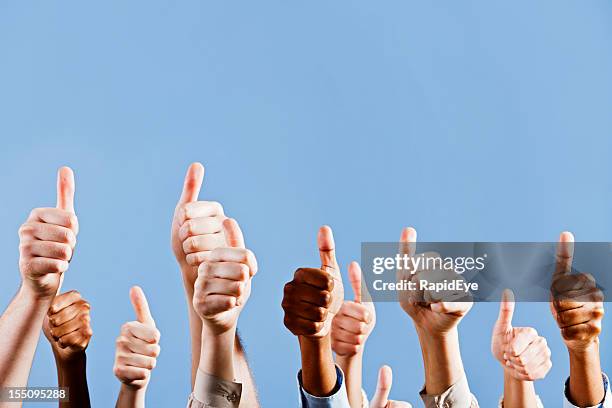 many hands give approving thumbs up against blue background - black thumbs up white background stock pictures, royalty-free photos & images