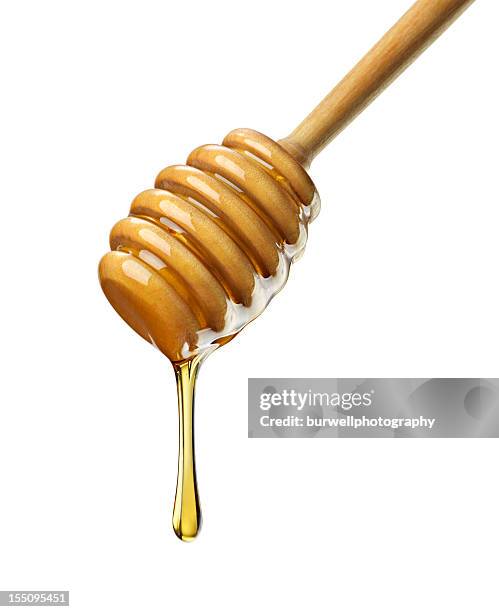 organic honey with wooden dipper against white - sticking stock pictures, royalty-free photos & images