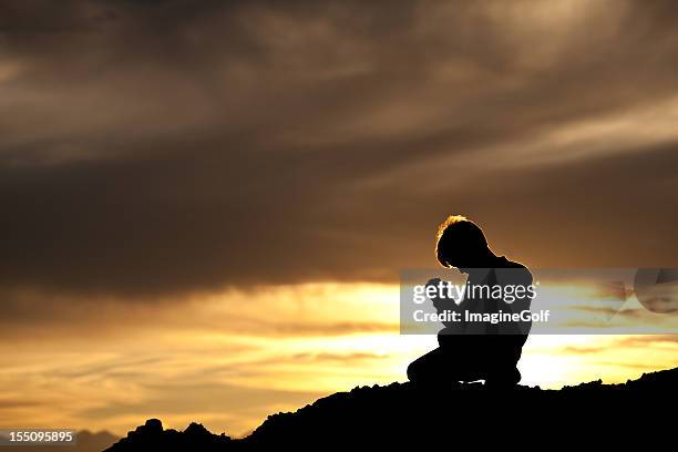 silhouette der jungen kaukasischen junge beten - god is love stock-fotos und bilder