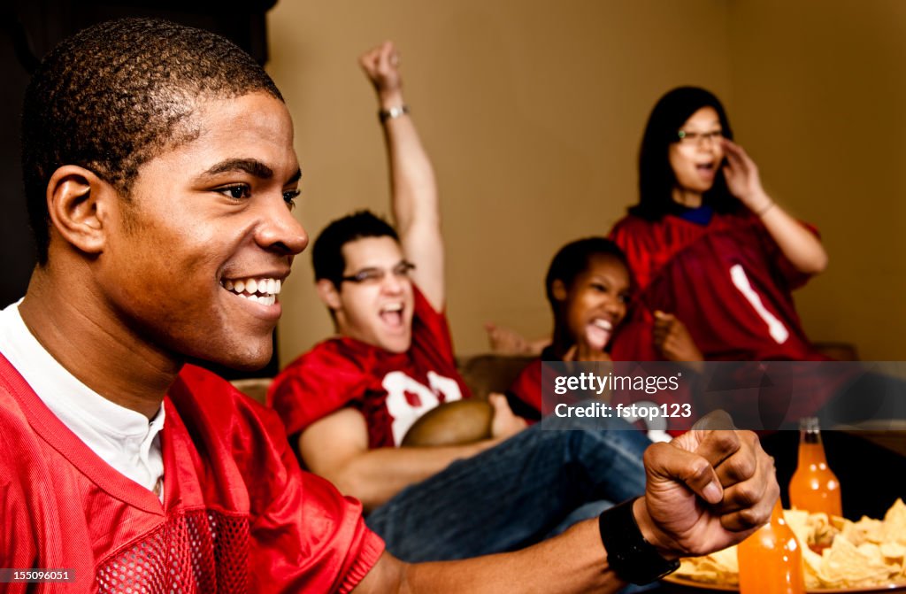 Football fans at home watching, cheering. Sports game on television.