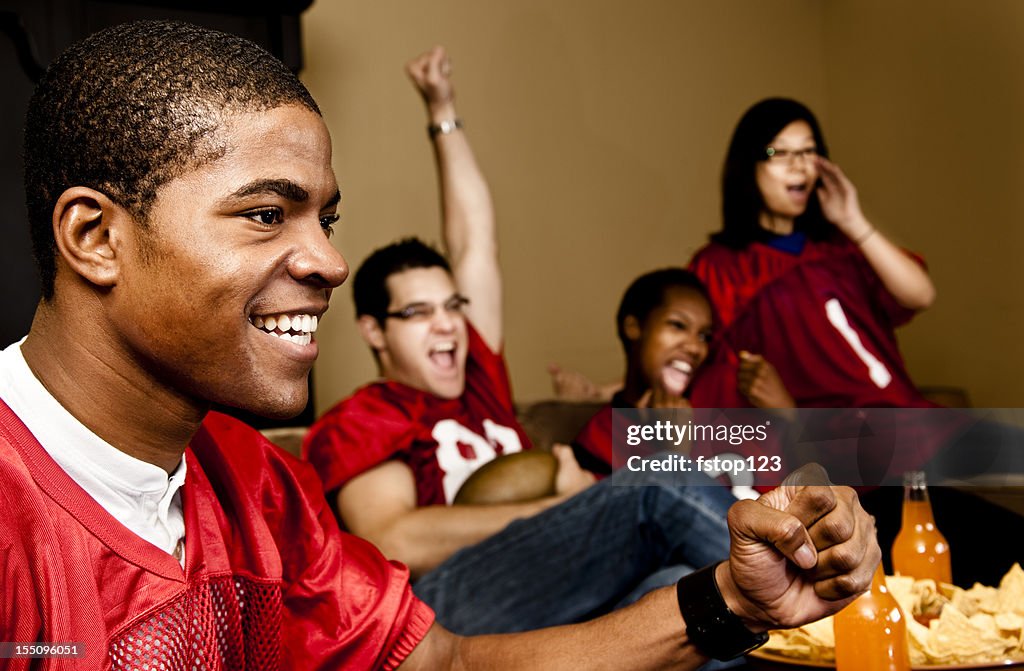 Football fans at home watching, cheering. Sports game on television.