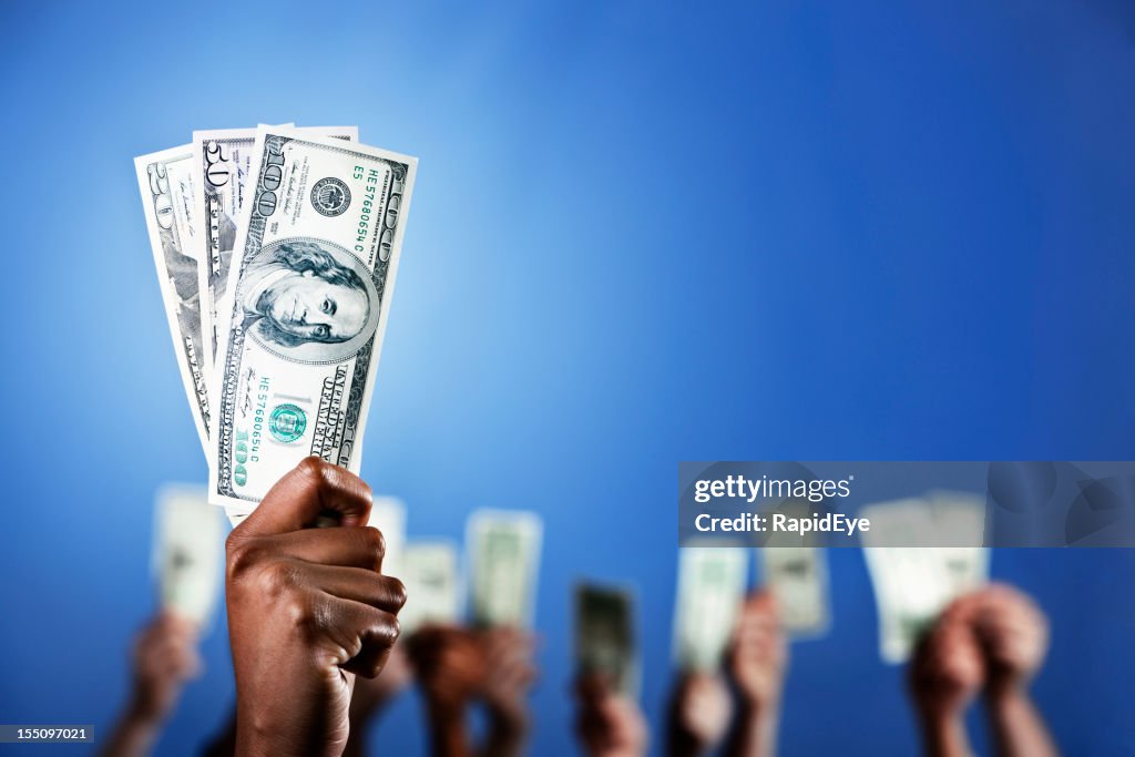 Selective focus, many fists holding up money