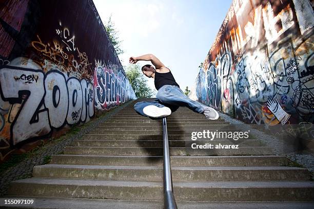 junger mann springt über die mauer - berlin graffiti stock-fotos und bilder