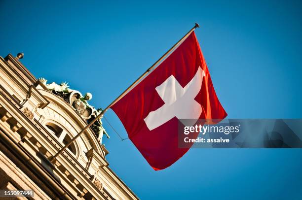 swiss flag waving on historic building - swiss culture stock pictures, royalty-free photos & images