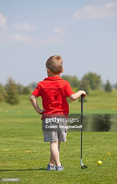 young boy holding golf club on course - golf lessons stock pictures, royalty-free photos & images