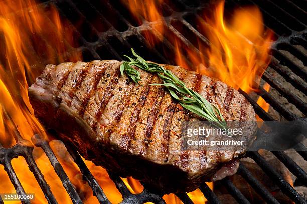 ribeye steak on grill with fire - ribeye biefstuk stockfoto's en -beelden