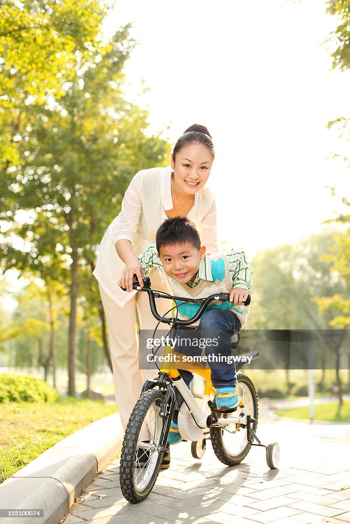 Maman apprend son fils dans le parc d'équitation un vélo