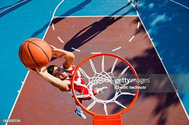 young male player making basket - slam dunk stock pictures, royalty-free photos & images