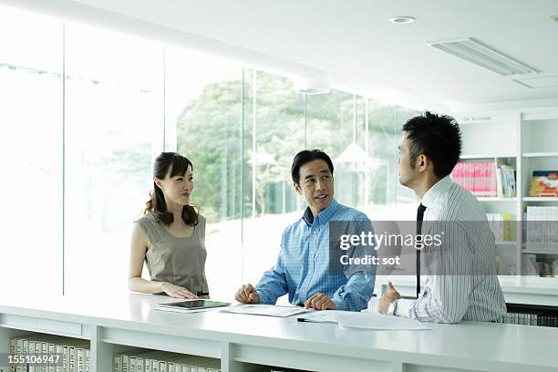 coworkers discussing project in office library - conference 2012 day 3 stockfoto's en -beelden