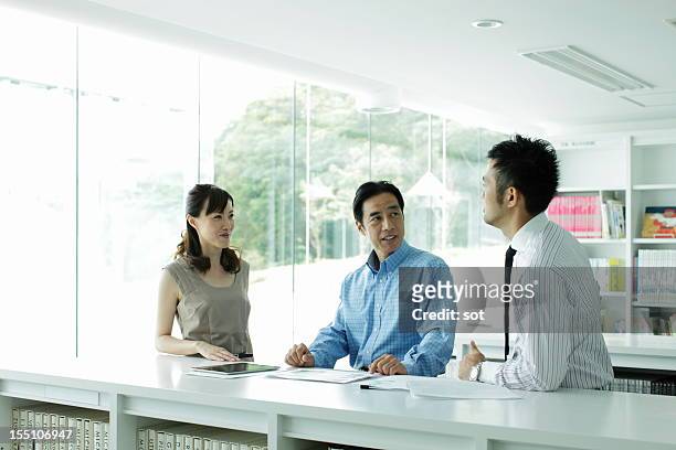 coworkers discussing project in office library - business meeting three people stock pictures, royalty-free photos & images
