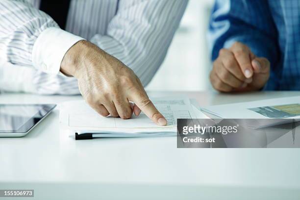 businessman pointing finger at plans - documento foto e immagini stock