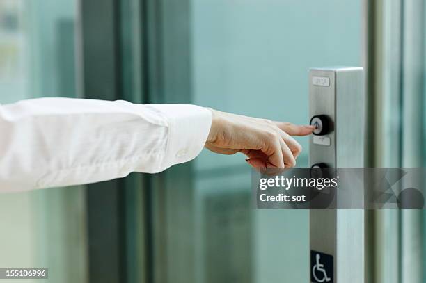 businesswoman pressing button for elevator - lift foto e immagini stock