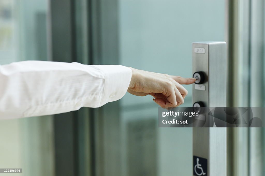 Businesswoman pressing button for elevator