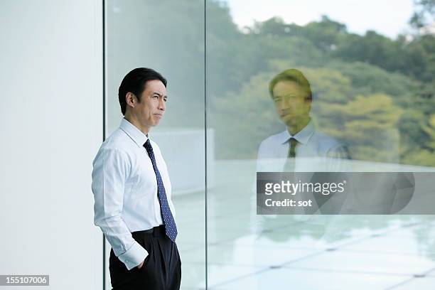 businessman looking out window in office hallway - skjorta och slips bildbanksfoton och bilder