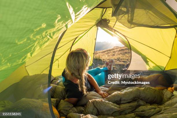 woman bikepacking and camping, she lies inside her tent looking out at the view - bivouac stock pictures, royalty-free photos & images