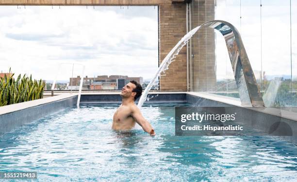 homme heureux dans la piscine du spa se faisant masser le dos - piscine thermale photos et images de collection