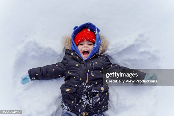 young girl lays in snow making a snow angel - bundle stock pictures, royalty-free photos & images