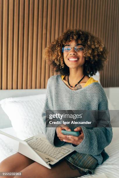 portrait of a young woman sitting on the bed - open enrollment stock pictures, royalty-free photos & images