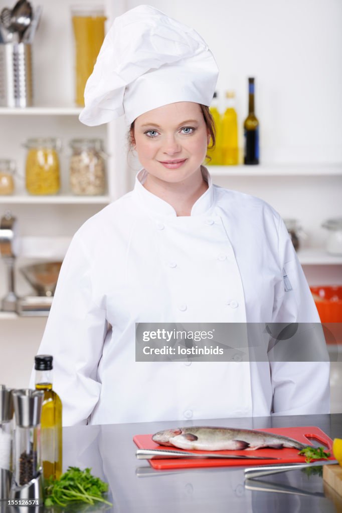 Female Caucasian Chef Preparing Fish In A Commercial Kitchen