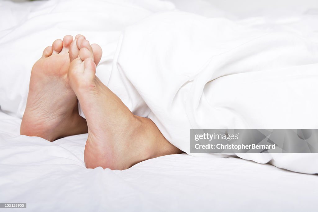 Woman bare feet under blanket