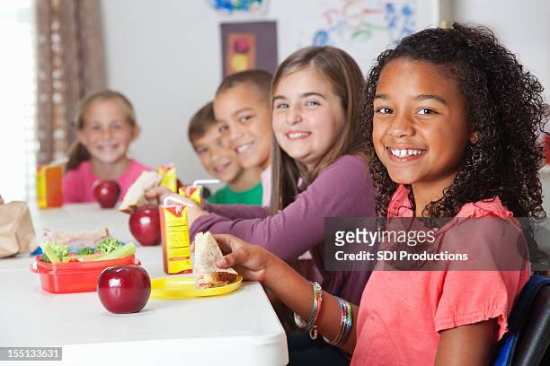 cute elementary children having lunch at school - child holding apples stockfoto's en -beelden
