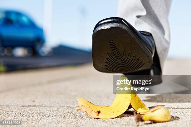 painful slip coming as man's foot approaches banana peel - wegduiken stockfoto's en -beelden