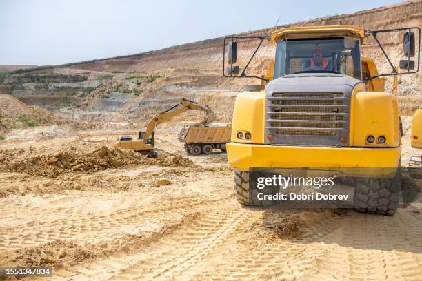 a heavyweight truck driver with his truck on a kaolin quarry. - trucker hat stock pictures, royalty-free photos & images