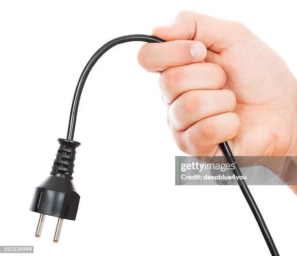 black electric cable in male hand on white - plugging in stockfoto's en -beelden