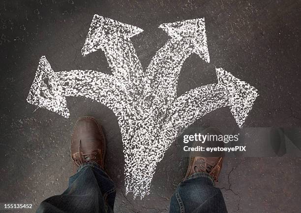 hombre de pie con cuatro caminos que elegir - calle bifurcada fotografías e imágenes de stock