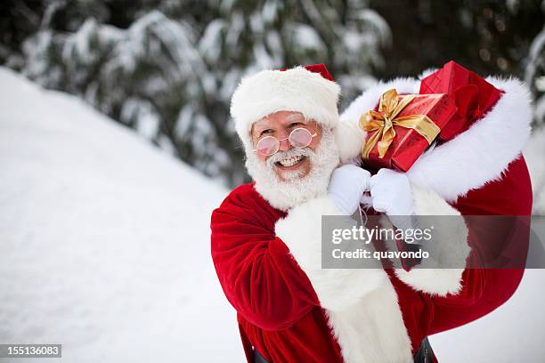 allegro babbo natale camminare nella neve di inverno con i regali di natale - santa sack foto e immagini stock