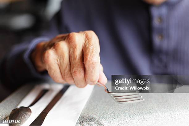 senior mann holding gabelung im restaurant tisch - spoon in hand stock-fotos und bilder