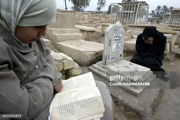 An Iraqi girl reads the Koran while her mother recites the Fatiha, the opening Surat of Koran, over a tomb written on its headstone "late aggrieved...