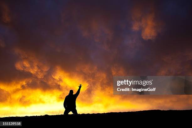 hand to heaven - man praying on his knees stock pictures, royalty-free photos & images