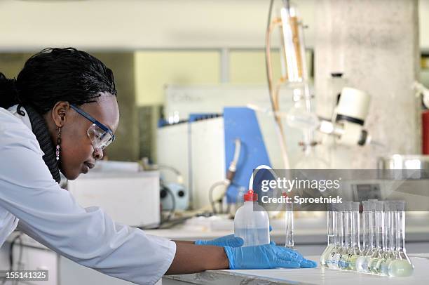 biochemiker decants fluid in glaskolben seitenansicht - destillation stock-fotos und bilder