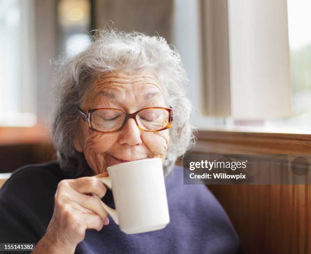 mujer senior funny face sonrisa con una taza de café - sólo mujeres mayores fotografías e imágenes de stock