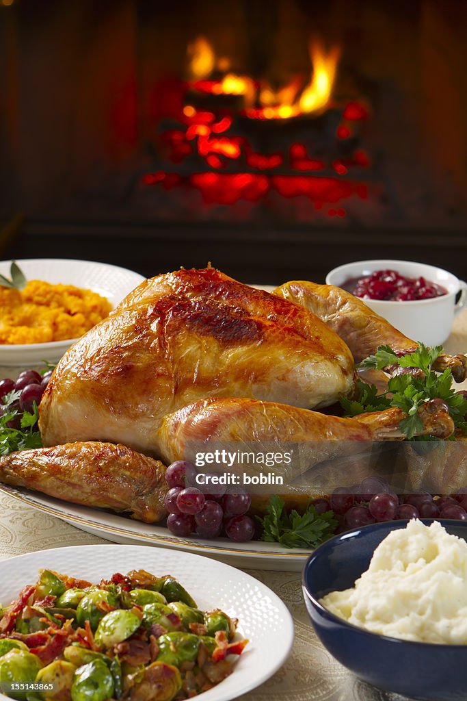 Cooked turkey on a dish with grapes in front of open fire