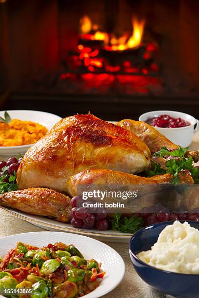 cooked turkey on a dish with grapes in front of open fire - christmas table turkey stock pictures, royalty-free photos & images