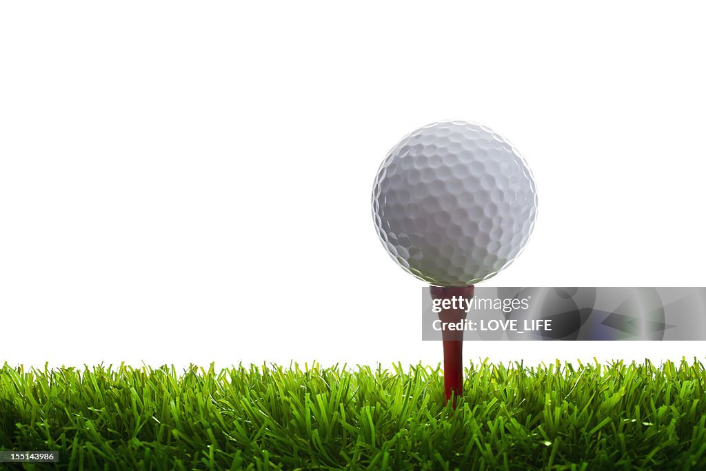 Golfball und Tee auf Gras