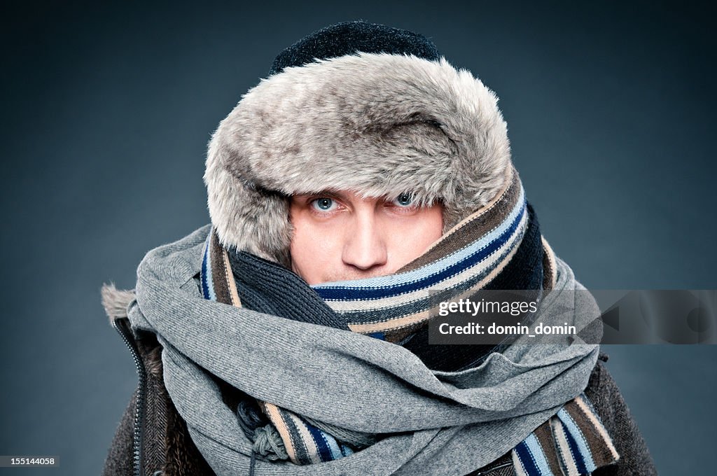 Hombre en ropa de invierno está estrechamente tarjeta, tapa, scarves